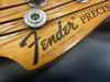 Close-up of Fender Precision bass guitar headstock with tuning pegs and worn wood finish