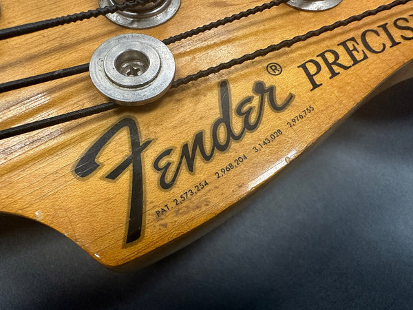 Close-up of Fender Precision bass guitar headstock with tuning pegs and worn wood finish