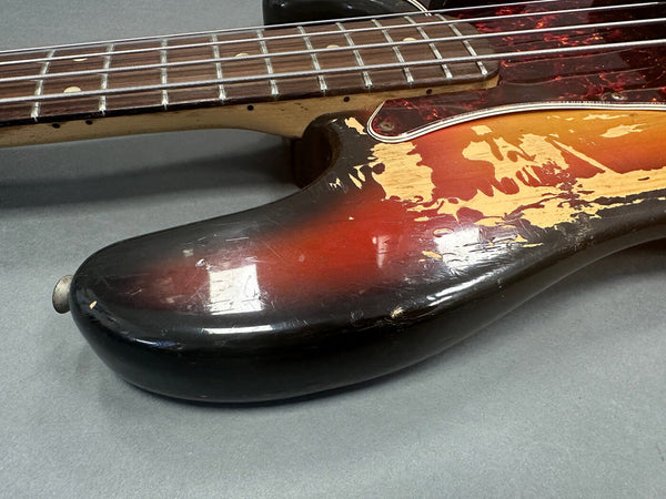 Close-up of worn sunburst electric guitar body and neck with visible paint chips and scratches on grey background