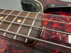 Close-up view of electric bass guitar fretboard and metal strings on tortoiseshell pickguard with worn black guitar body edges