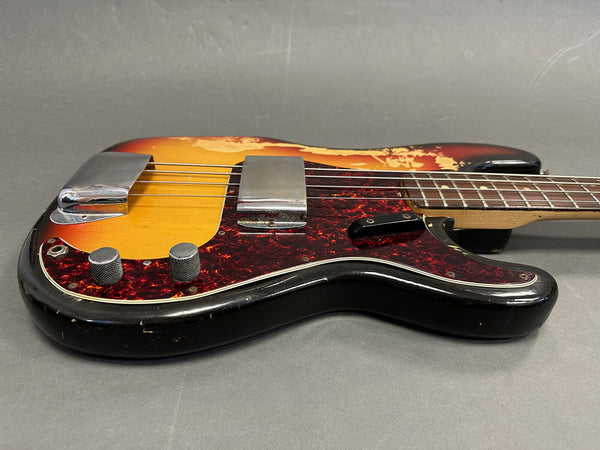 Vintage sunburst electric bass guitar with tortoiseshell pickguard and chrome hardware on gray background