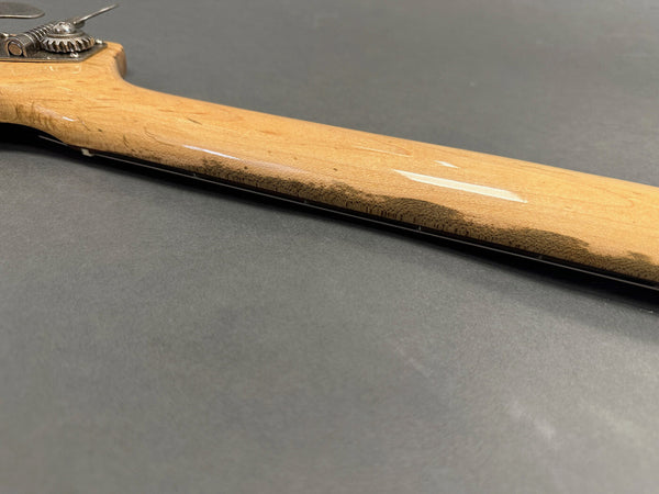 Close-up of the natural wood guitar neck and tuning peg on a gray background, showcasing smooth finish and wood grain details