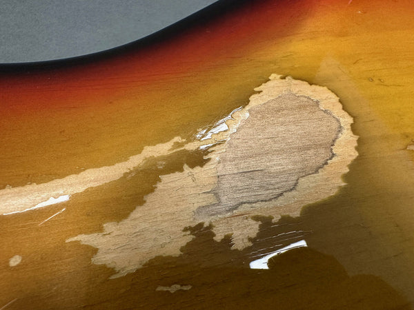 Close-up of sunburst finish guitar body with worn and chipped paint revealing natural wood underneath