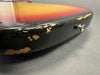 Close-up of worn and chipped sunburst guitar body edge showing paint wear and strap button on black finish