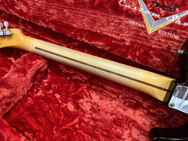 Close-up of Fender guitar neck with maple wood and dark skunk stripe detail, resting on red plush Fender Limited Edition guitar case interior
