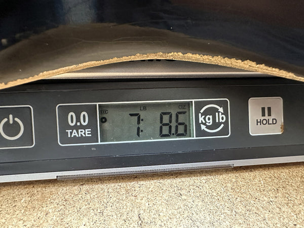 Digital scale showing a guitar weight of 7 pounds 8.6 ounces with tare and unit conversion buttons visible.
