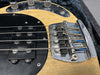 Close-up image of natural wood finish electric bass guitar bridge and pickups with chrome hardware and black pickguard