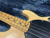 Close-up of vintage natural wood bass guitar neck and black pickguard on blue plush case interior