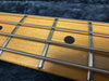 Close-up of maple guitar fretboard with metal frets, black dot inlay, and steel guitar strings on dark background
