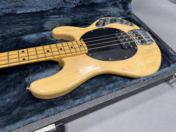 Vintage natural finish electric bass guitar with black pickguard in open hard case with plush interior