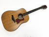Taylor acoustic guitar with natural wood finish, tortoiseshell pickguard, and black bridge pins on white background