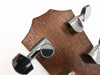 Close-up of guitar tuning pegs on wooden headstock with chrome machine heads for precise tuning at Coffee House Guitars