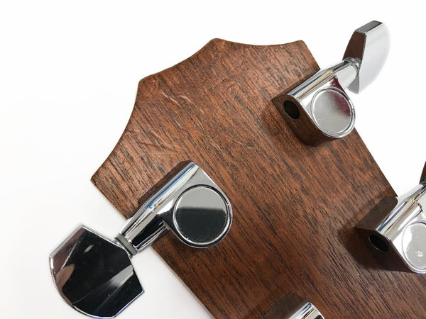 Close-up of guitar tuning pegs on wooden headstock with chrome machine heads for precise tuning at Coffee House Guitars