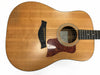 Taylor acoustic guitar with natural wood finish, tortoise shell pickguard, and black bridge pins on white background