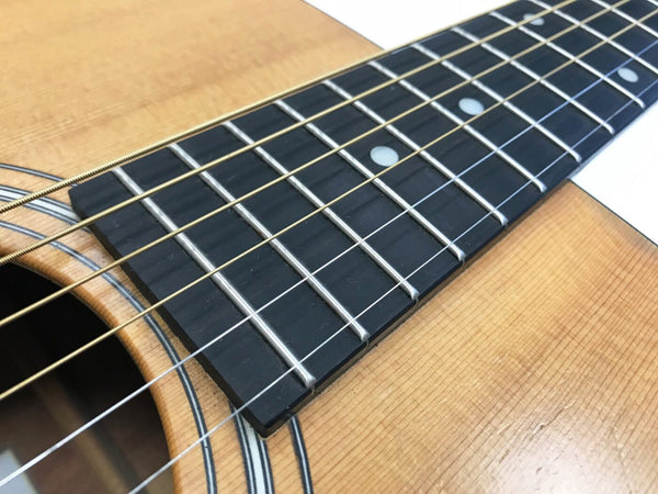 Close-up of acoustic guitar fretboard and soundhole with steel strings and wooden body