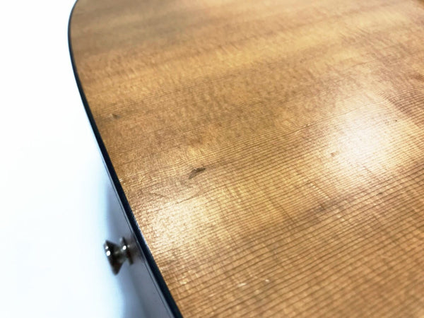 Close-up of acoustic guitar body showing natural wood grain and strap button on side