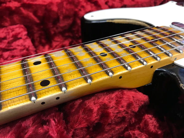 Close-up of electric guitar maple neck and fretboard with metal frets and strings on red plush case interior