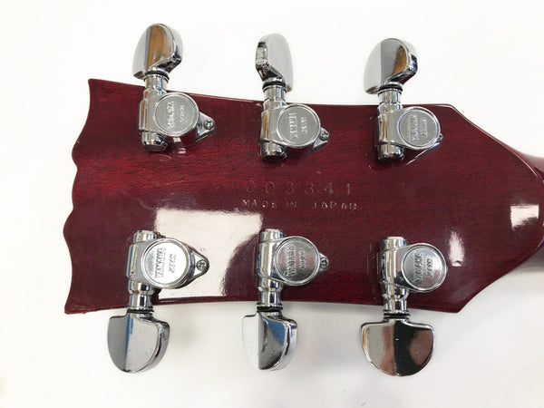 Close-up of red guitar headstock with six chrome Yamaha tuning pegs and "Made in Japan" stamped on the back