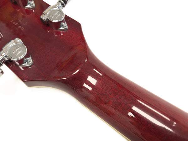 Close-up of glossy red guitar neck and headstock with chrome tuning pegs on white background