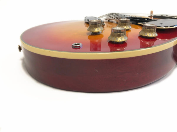 Close-up view of sunburst electric guitar body with golden yellow binding and transparent control knobs on white background