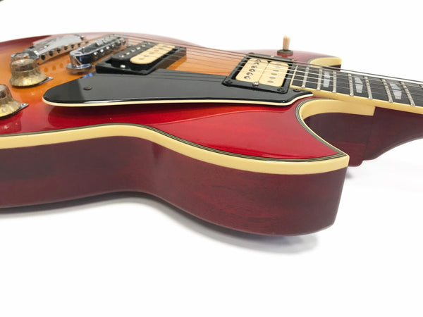 Close-up of vintage electric guitar body with sunburst finish, black pickguard, cream binding, humbucker pickups, and control knobs on white background