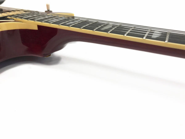 Close-up side view of maroon electric guitar neck and fretboard with cream binding on white background