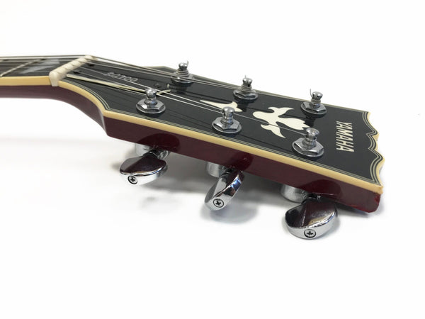 Close-up of Yamaha SA100 electric guitar headstock with tuning pegs and bird inlay on black background