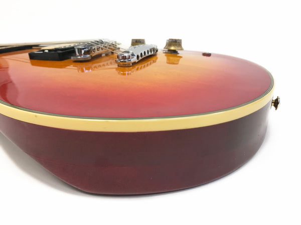 Close-up side view of sunburst electric guitar body with cream binding and chrome bridge on white background