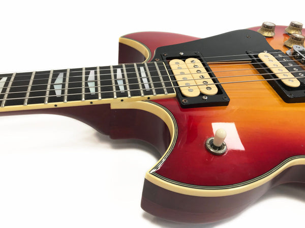 Close-up of sunburst electric guitar body and neck with humbucker pickups and toggle switch on white background