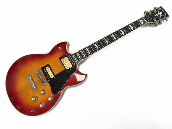Yamaha electric guitar with sunburst finish, dual humbucker pickups, black pickguard, and distinctive inlay designs on fretboard and headstock on white background