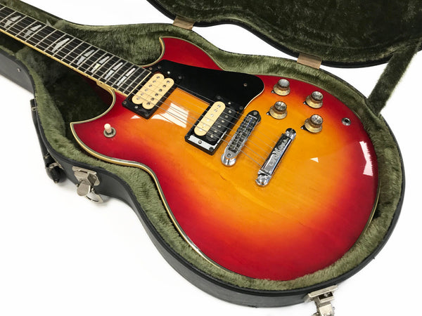 Vintage sunburst electric guitar with dual humbucker pickups and chrome hardware in green plush-lined hard case